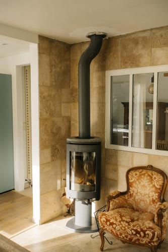 a fireplace in a living room with a chair at Beautiful house in the heart of its pine forest - private pool in Les Taillades