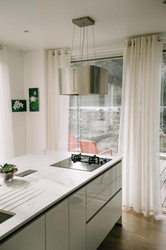 a white kitchen with a stove and a window at Beautiful house in the heart of its pine forest - private pool in Les Taillades