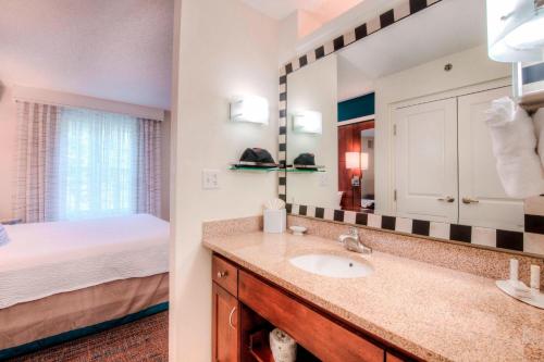 Residence Inn by Marriott Chapel Hill في تشابل هيل: حمام مع حوض وسرير ومرآة