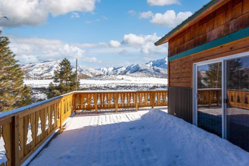 a deck with a view of snow covered mountains at Twin Pines Cabin in Wilderness Ranch on Hwy 21, AMAZING Views, 20 ft ceilings, fully fenced yard, pet friendly, , Go paddle boarding at Lucky Peak, or snowshoeing in Idaho City and take in the hot springs, sleeps 10! in Boise