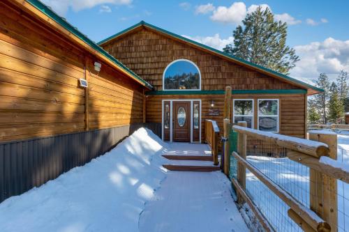 a log cabin with snow on the porch at Twin Pines Cabin in Wilderness Ranch on Hwy 21, AMAZING Views, 20 ft ceilings, fully fenced yard, pet friendly, , Go paddle boarding at Lucky Peak, or snowshoeing in Idaho City and take in the hot springs, sleeps 10! in Boise