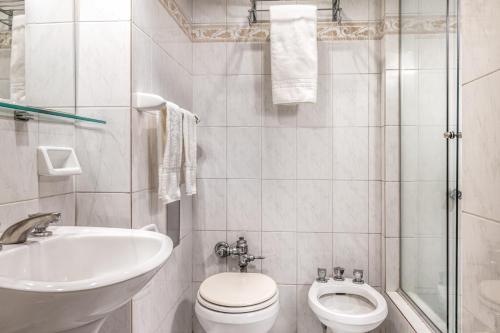 a white bathroom with a toilet and a sink at Up Retiro in Buenos Aires