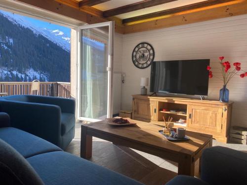 ein Wohnzimmer mit einem TV, einem Sofa und einem Tisch in der Unterkunft Apartment Margherita in Sedrun