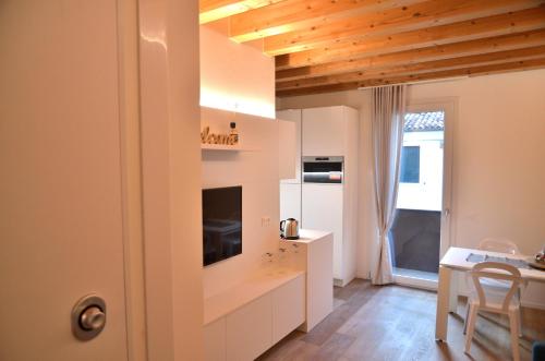 una pequeña cocina con armarios blancos y una mesa en CA MATTA luxury and relax, en Noale