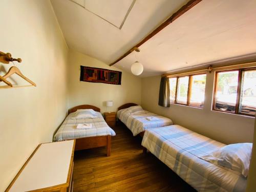 Habitación con 3 camas y mesa. en Flying Dog Hostel Cusco, en Cusco