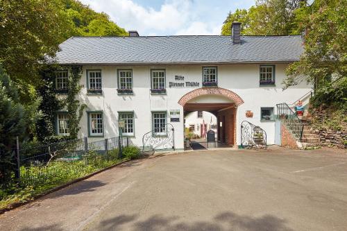 a white house with an archway and a driveway at Ferienwohnung "Alte Pleiner Mühle" in Plein