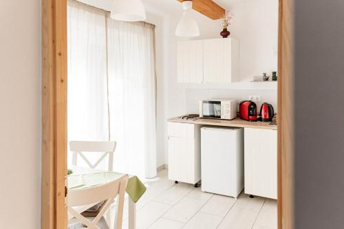 a kitchen with white cabinets and a table and a microwave at Levendula Apartmanház in Badacsonytomaj