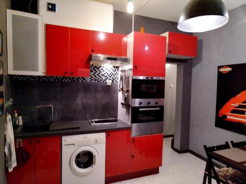 - une cuisine avec des placards rouges et un lave-linge dans l'établissement Appartement avec terrasse 10M2 centre ville 300 m Sète, à Sète