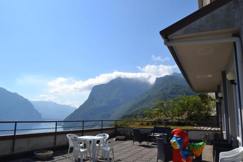 a balcony with tables and chairs and a view of mountains at Appartamenti Lago di Como in Valbrona