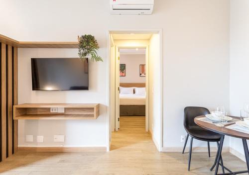 a living room with a table and a television on a wall at Consolação by Charlie in Sao Paulo