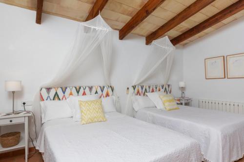 ソリェルにあるFinca Rural Es Pujolの白い壁と木製の天井が特徴の客室で、ベッド2台が備わります。