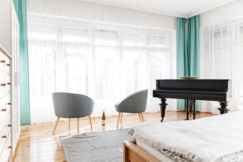 a bedroom with a piano and two chairs at Levendula Apartmanház in Badacsonytomaj
