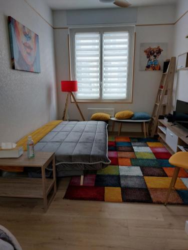 Schlafzimmer mit einem Bett, einem Tisch und einem Teppich in der Unterkunft L'Appartement Gabriel T2 in Bergerac