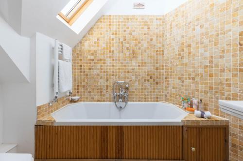 een badkamer met een ligbad en een wastafel bij Little Maunditts Cottage - quiet location in charming Cotswold village in Sherston