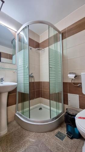 een badkamer met een douche, een wastafel en een toilet bij Hotel Azur in Eforie Nord