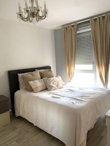 1 dormitorio con 1 cama con lámpara de araña y ventana en Appartement moderne et spacieux proche Paris, en Alfortville