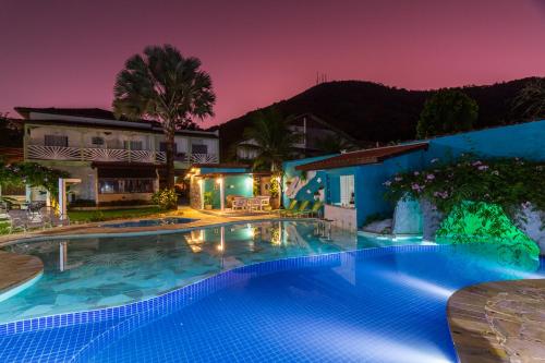 a swimming pool in front of a house at night at Pousada Daleste in Angra dos Reis