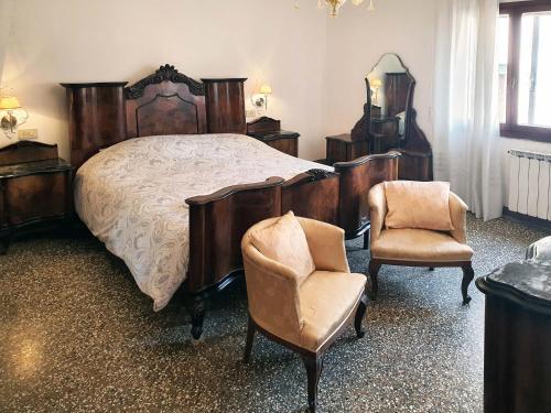 um quarto com uma cama e um par de cadeiras em CasaGiulietta em Veneza