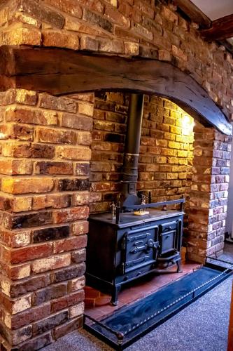 a brick kitchen with a stove in a brick wall at Forget Me Not Cottage in Ironbridge