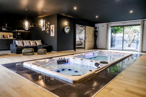 a large room with a jacuzzi tub in the middle of the room at Au domaine des anges, 3 gîtes luxueux avec Jacuzzi privatif, sauna, mini-piscine, piscine extérieure chauffée en saison in Bain-de-Bretagne