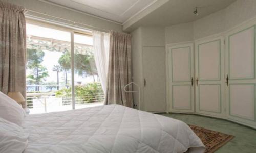 une chambre avec un grand lit et une grande fenêtre dans l'établissement Superbe Appartement vue mer Pointe Croisette, à Cannes