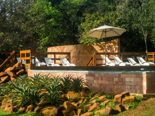 einen Pool mit weißen Liegestühlen und einem Sonnenschirm in der Unterkunft Momora distrito selva in Santa Ana