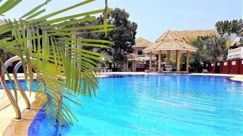 una piscina blu con una palma in primo piano di POTTERLAND Luxury Pool Villa Pattaya Walking Street 6 Bedrooms a Pattaya Sud