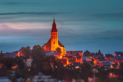 a city with a clock tower at night at Berghotel Steiger - Erzgebirge in Schneeberg