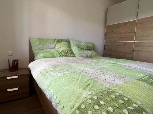 a bedroom with a green bed with a wooden headboard at Ferienwohnungen Fritze Bürger in Schiefling am See