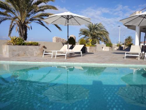 uma piscina com duas cadeiras e um guarda-sol em Boutique Hotel Colina del Emperador em La Manga del Mar Menor