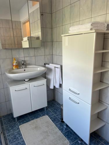 een witte badkamer met een wastafel en een spiegel bij Ferienwohnungen Fritze Bürger in Schiefling am See