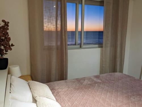 a bedroom with a bed and a window with the ocean at Apartamento en la playa con garaje in Cádiz