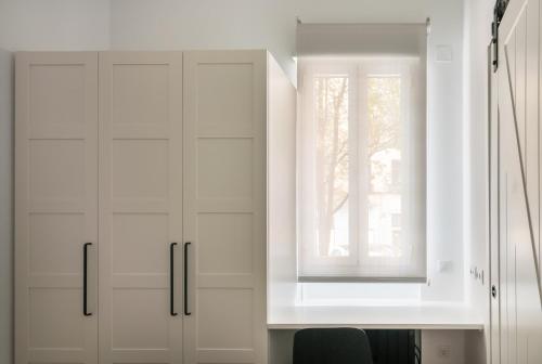 een witte keuken met witte kasten en een raam bij Loft Retiro in Madrid