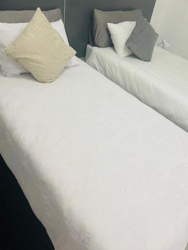 two beds with white sheets and pillows next to each other at Moh Ville Guest House in Maseru