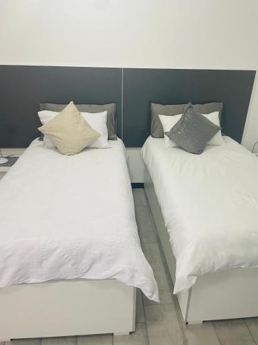 two beds with white sheets and pillows on them at Moh Ville Guest House in Maseru