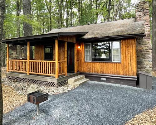 uma cabana de madeira com um alpendre na floresta em Mountain Springs Lake Resort em Stroudsburg