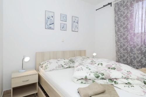 Un pequeño dormitorio con una cama con flores. en Apartments Punta, en Privlaka