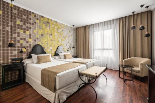 um quarto de hotel com uma cama grande e uma cadeira em Hotel Rio Badajoz em Badajós