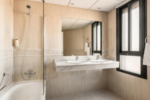 a bathroom with two sinks and a shower at Hotel Rio Badajoz in Badajoz