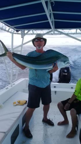 a man holding a fish on a boat at FLOR DE PARAISO BUNGALOWS in Montezuma