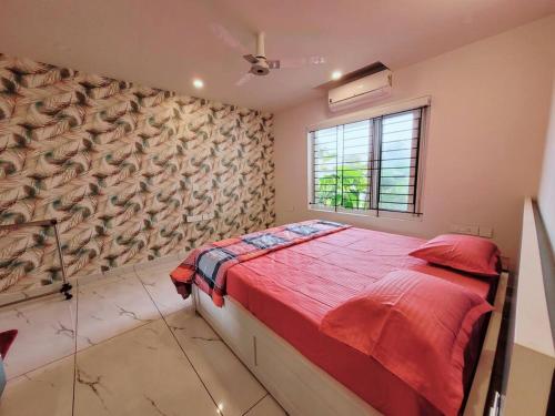 a bedroom with a bed with red sheets and a window at Gangothri in Trivandrum