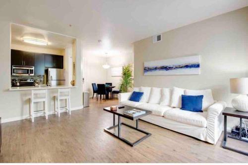 a living room with a white couch and a table at The Nest a Spacious 1 Bedroom Apartment with a Pool View in Los Angeles