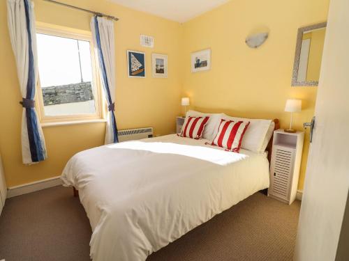 Un dormitorio con una gran cama blanca y una ventana en Seaforth, en Kilkee
