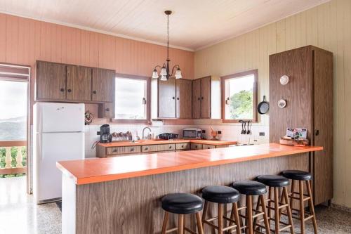a kitchen with wooden cabinets and a counter with bar stools at Cabin mountain view near Ponce slepts 8 in Ponce