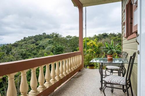 a balcony with a table and chairs and a view at Cabin mountain view near Ponce slepts 8 in Ponce