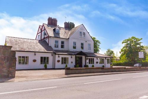 an old white building with a house on the side of the road at Woodcote Hotel in Hooton