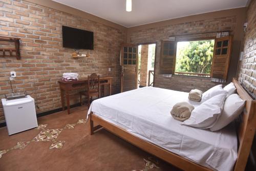a bedroom with a bed and a brick wall at Sítio do Bosco Park in Tianguá