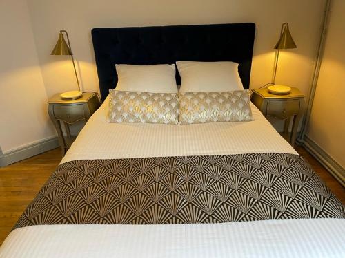 a bedroom with a bed with two lamps on two tables at Suites Mana - La Perle des Isles , Superbe maison Art déco avec balnéothérapie in Rethel