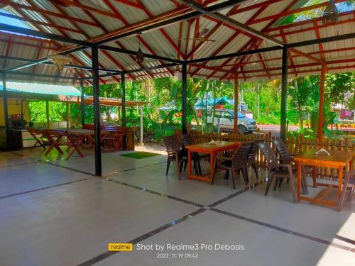 um restaurante com mesas e cadeiras de madeira sob um telhado em Green Imperial em Port Blair