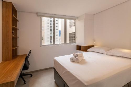 1 dormitorio con cama, escritorio y ventana en Conforto, 2 quartos e garagem perto da Faria Lima en São Paulo